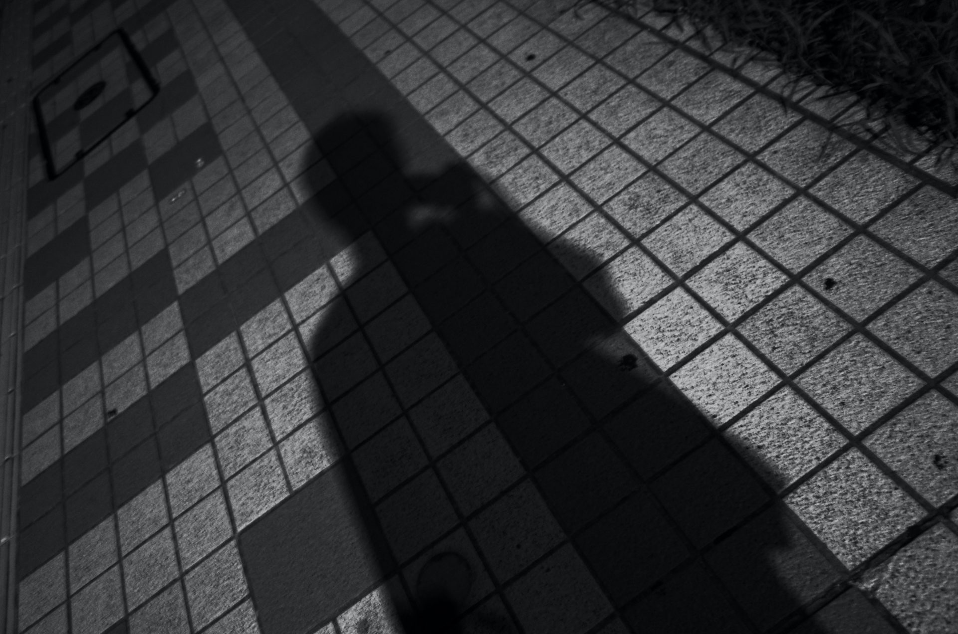 Shadow of person on gray concrete floor Schatten einer Person mit Handy in der Hand.