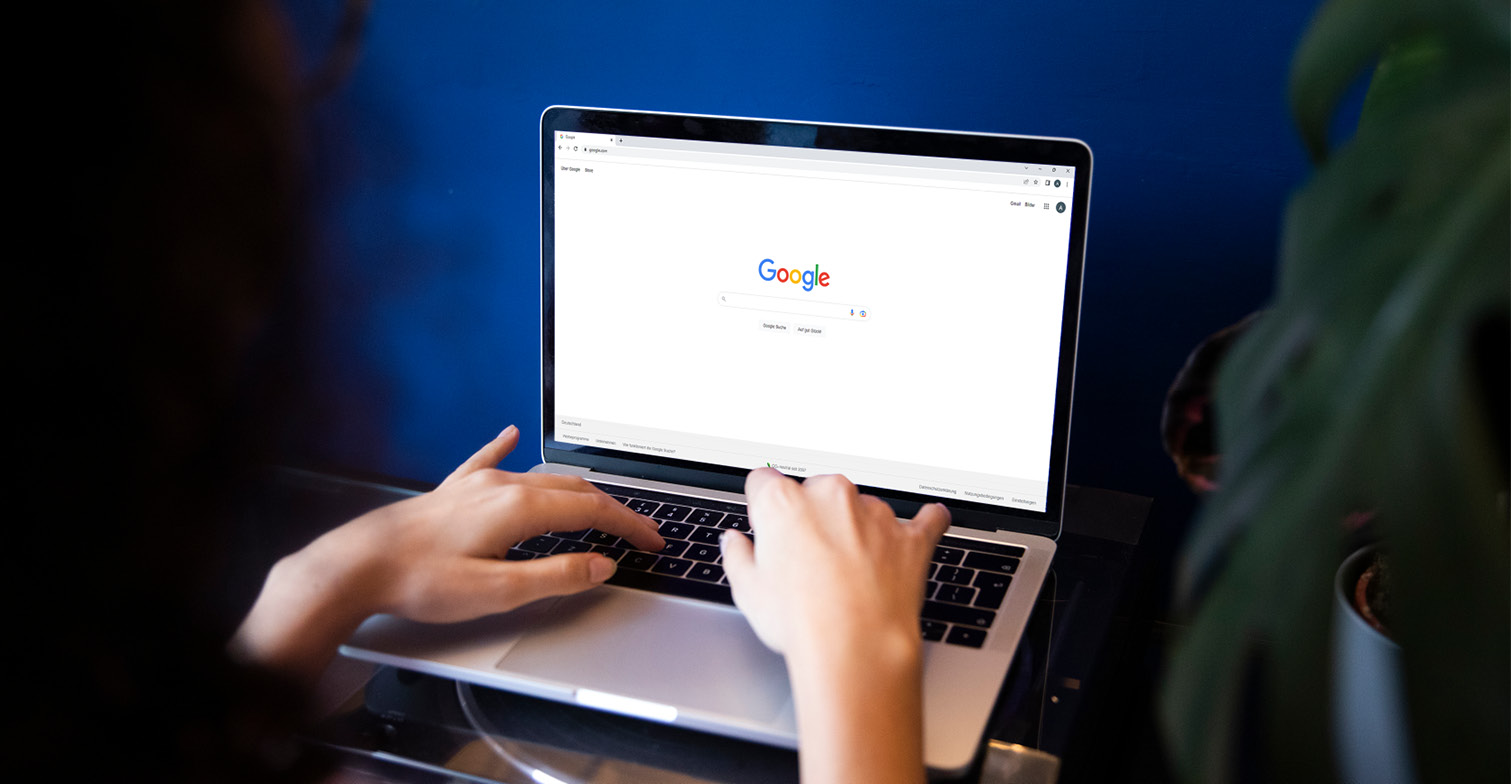 Person sitzt vor Laptop auf dem eine Google-Suche geöffnet ist.