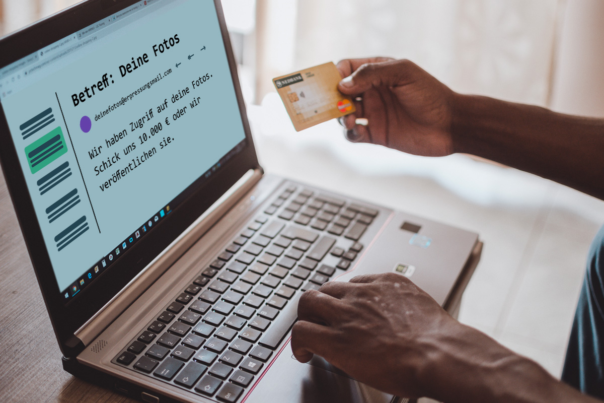 erpressung-artikelbild-c-scopio-talent-zukutu (1) Person hält Kreditkarte in der Hand, während sie vor ihrem Computer sitz, welcher eine Erpressungsnachricht zeigt.