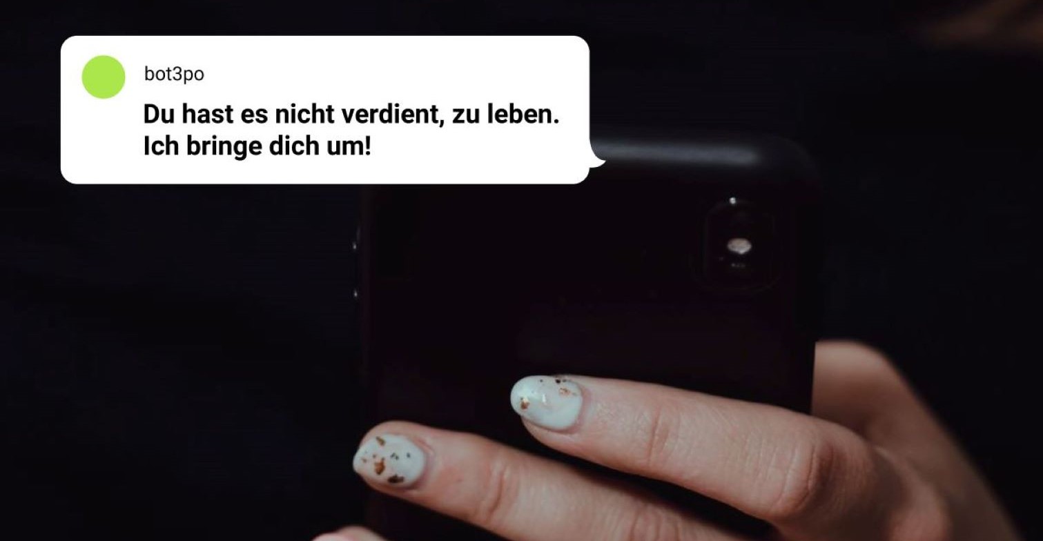 Hand hält ein Handy aus dem eine fiktive Drohnachricht: "Du hast es nicht verdient, zu leben. Ich bringe dich um!"