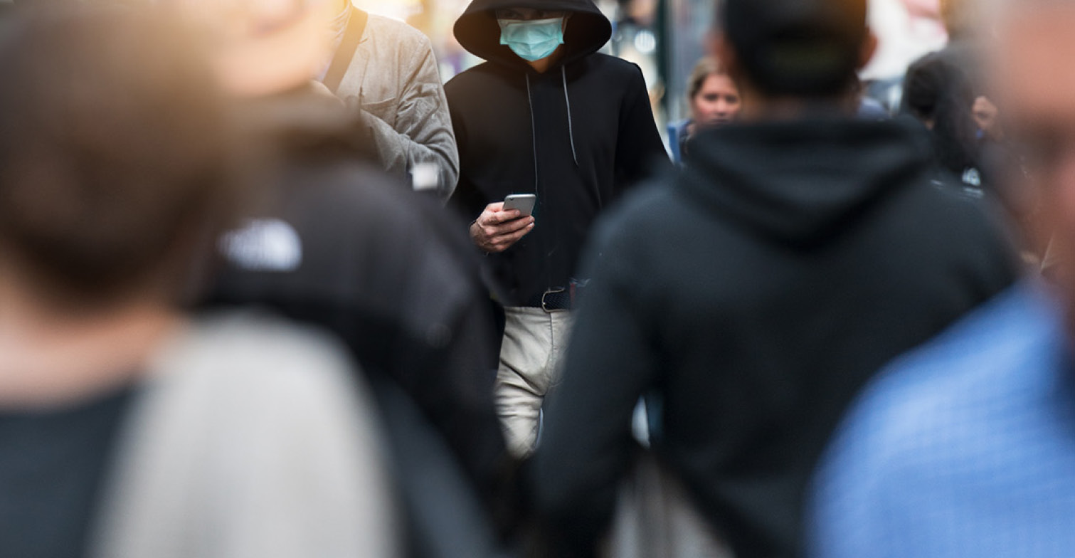 Menschenmenge, in der eine Person mit Handy im Fokus der Kamera steht.