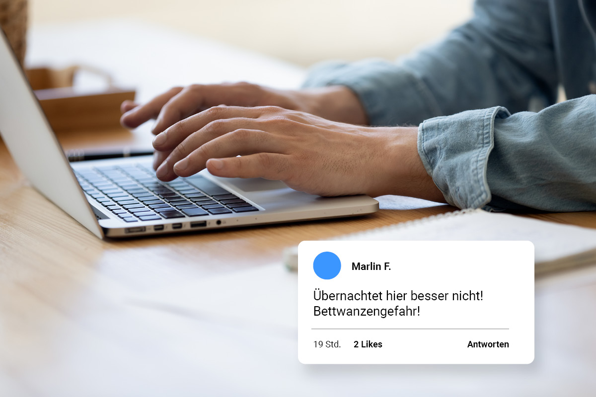 üble-nachrede-kommentar-artikelbild-c-shutterstock Person tippt an einem Laptop. Grafik einer Bewertung wird angezeigt mit Text: "Übernachtet hier nicht. Bettwanzen!!"