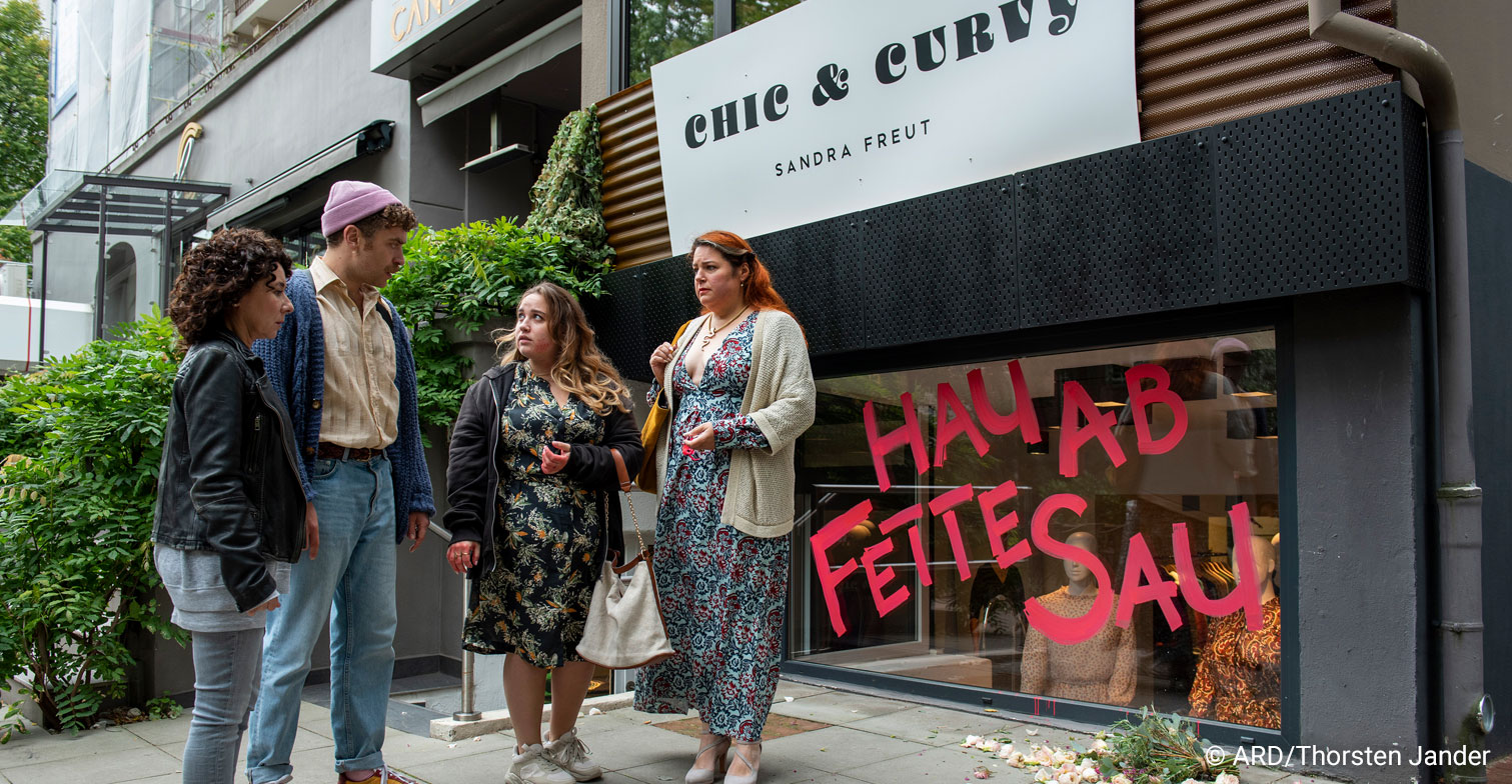 Mehrere Personen vor dem Laden Chic & Curvy und der Beleidigung: "Hau ab, fette Sau"