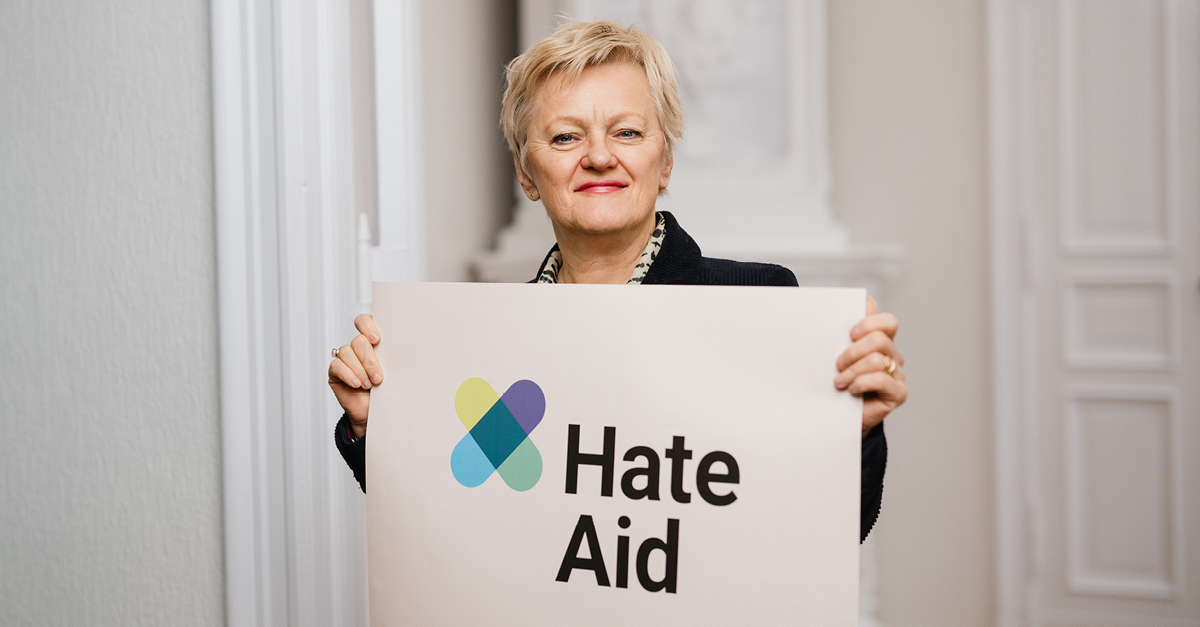 Renate Künast versus Meta - Portrait von Renate Künast mit HateAid-Schild "#FacebookDoYourJob"